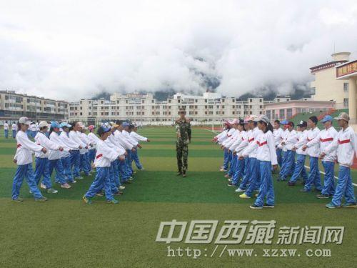 图为官兵指导参训学生军事动作