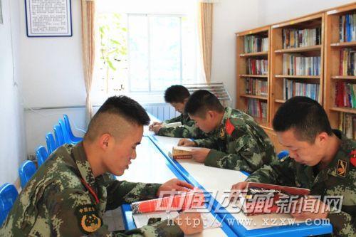图为官兵在闲暇时间在图书室观看红色书籍