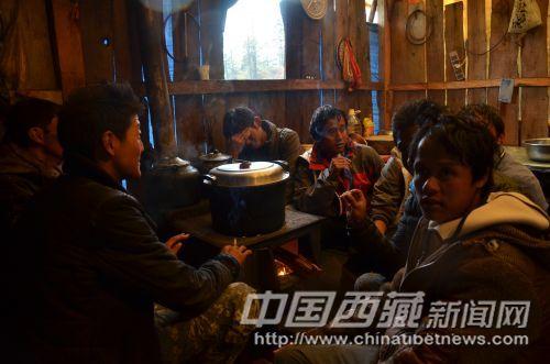 走了一天，背夫们都很疲惫，围坐在火炉边烤火休息。
