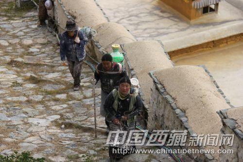 工人背着沉重的涂料行走在布达拉宫的台阶上