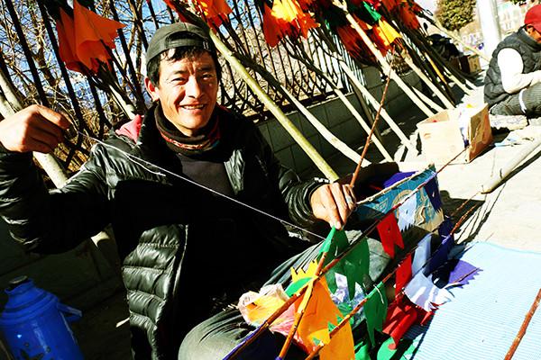 图为：1月23日上午，来自西藏日喀则市南木林县农民旦增平措，在藏历火鸡新年前来山南缝制、销售经幡树。他说，每天可以卖出30棵左右，每棵平均卖300元至150元不等，收入可观。曲杰 摄.jpg